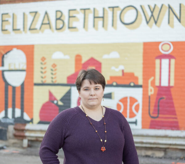 Katherine Leonard standing in front of Elizabethtown mural